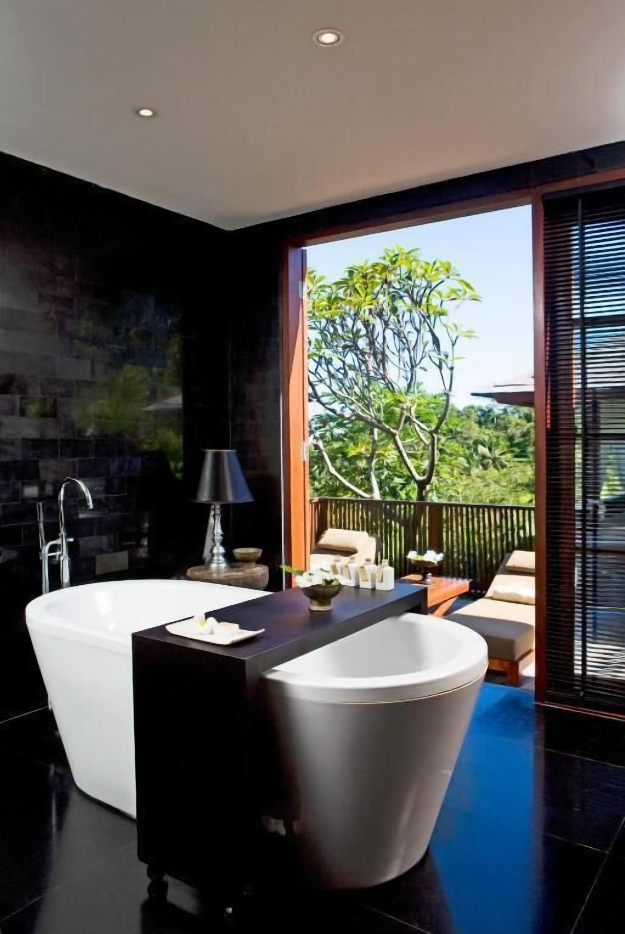 Une salle de bain moderne avec une baignoire sur pieds, un grand miroir et une fenêtre donnant sur un jardin luxuriant.