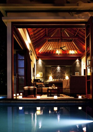 An indoor pool area with a ceiling fan, seating, and candles.