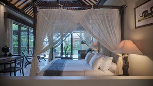 A bedroom with a canopy bed, a desk, and a view of the outdoors. - The Damai (Sukasada)
