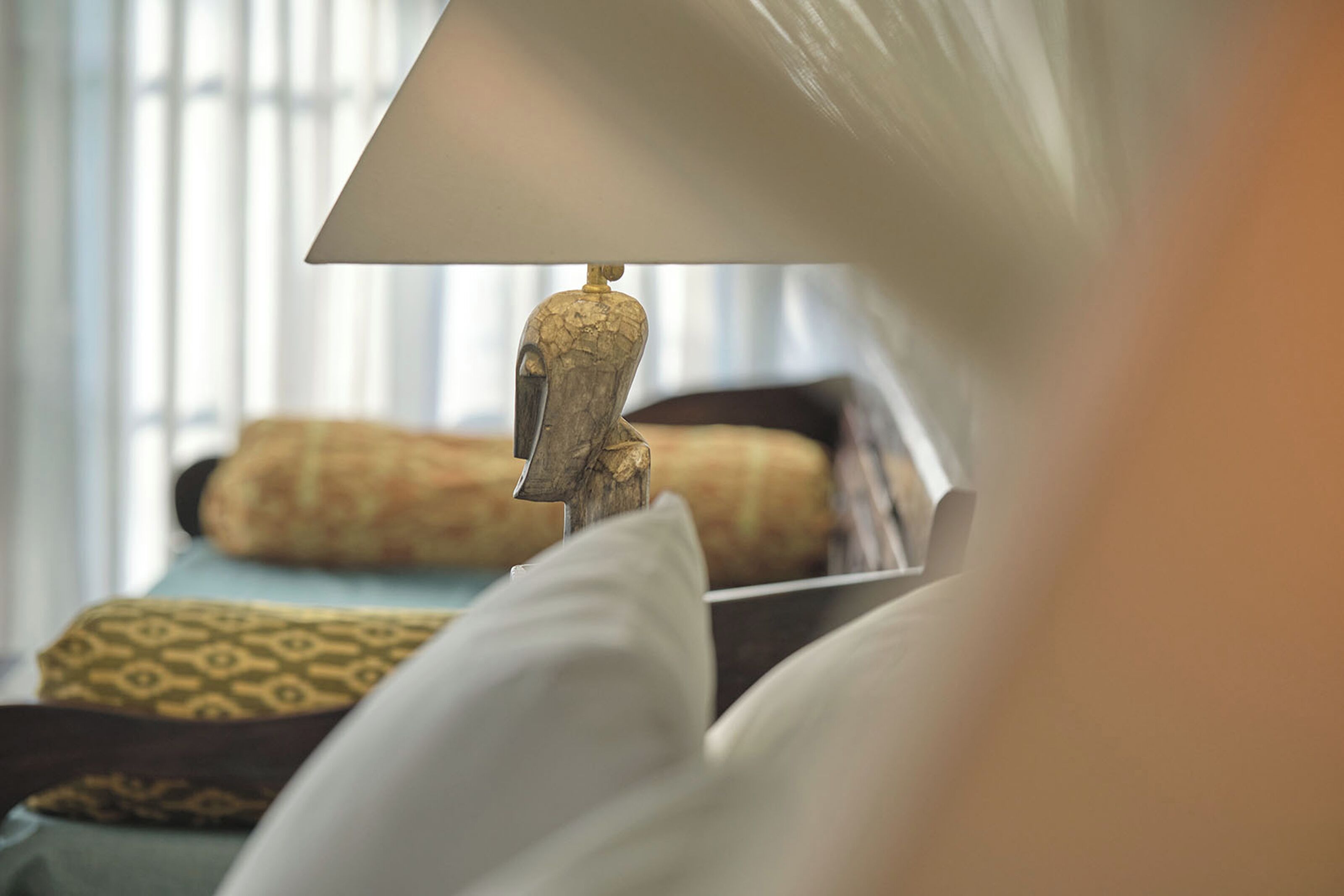A bed with patterned pillows and a lamp with a decorative base.