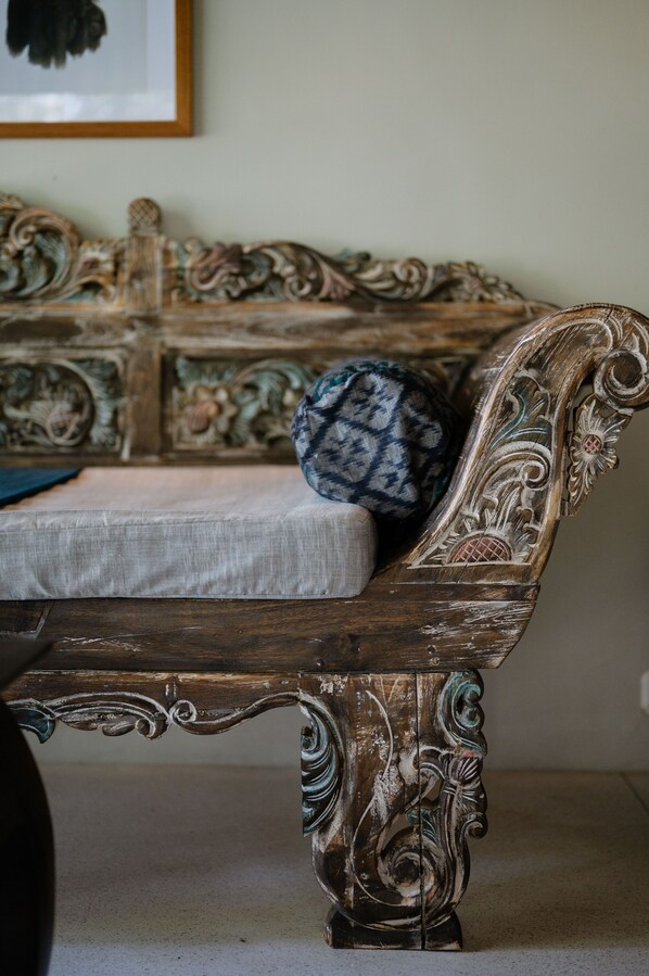 A vintage wooden bench with intricate carvings and a patterned cushion.