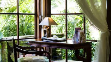 A room with a large window, a wooden desk, a chair, and a lamp.