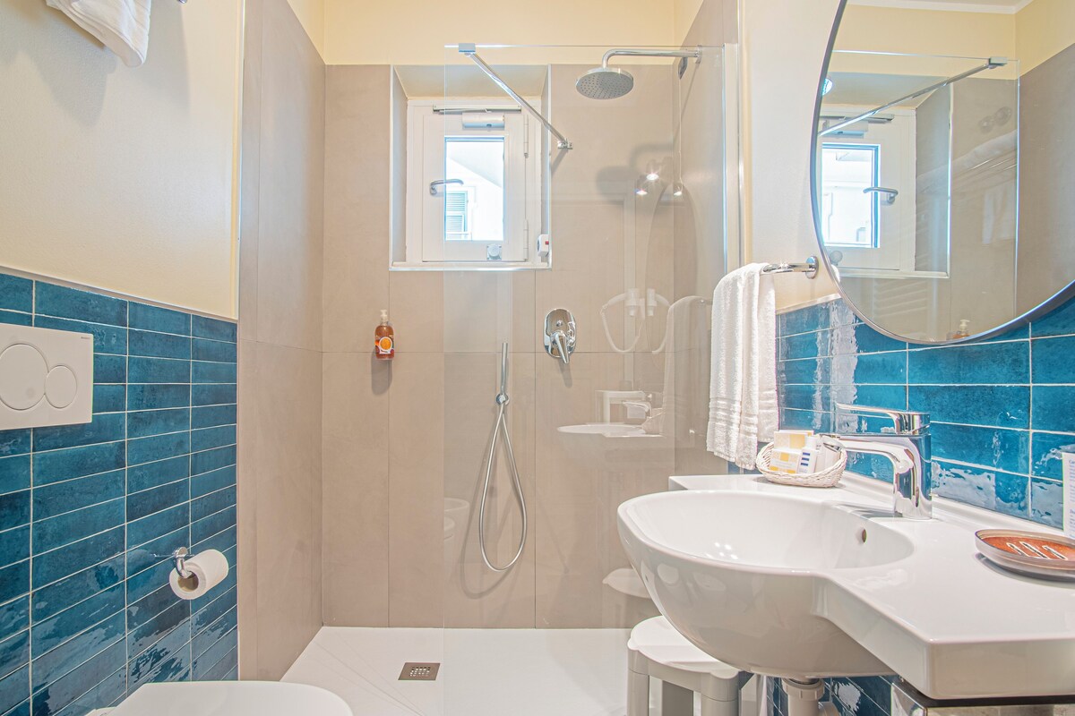 A bathroom with a shower, a sink, a toilet, and a mirror.