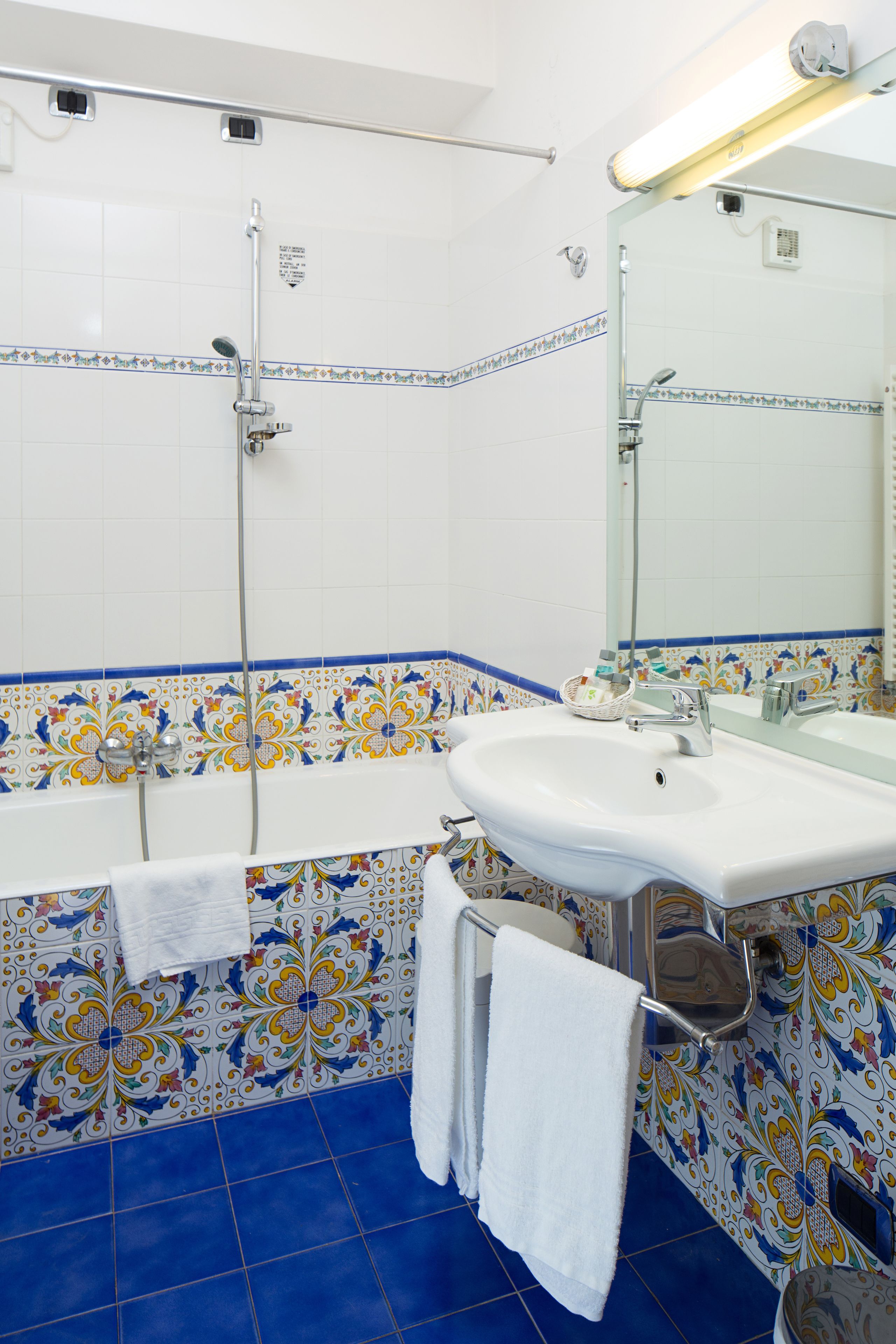 A bathroom with a bathtub, a sink, and a shower. There are towels hanging on the wall.