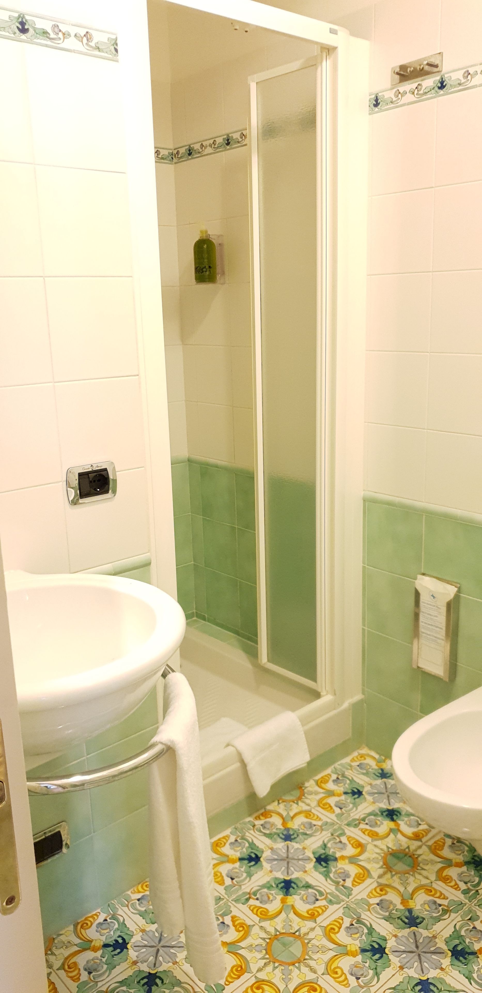 Ein Badezimmer mit Dusche, zwei Waschbecken und einem gefliesten Boden mit Blumenmuster.