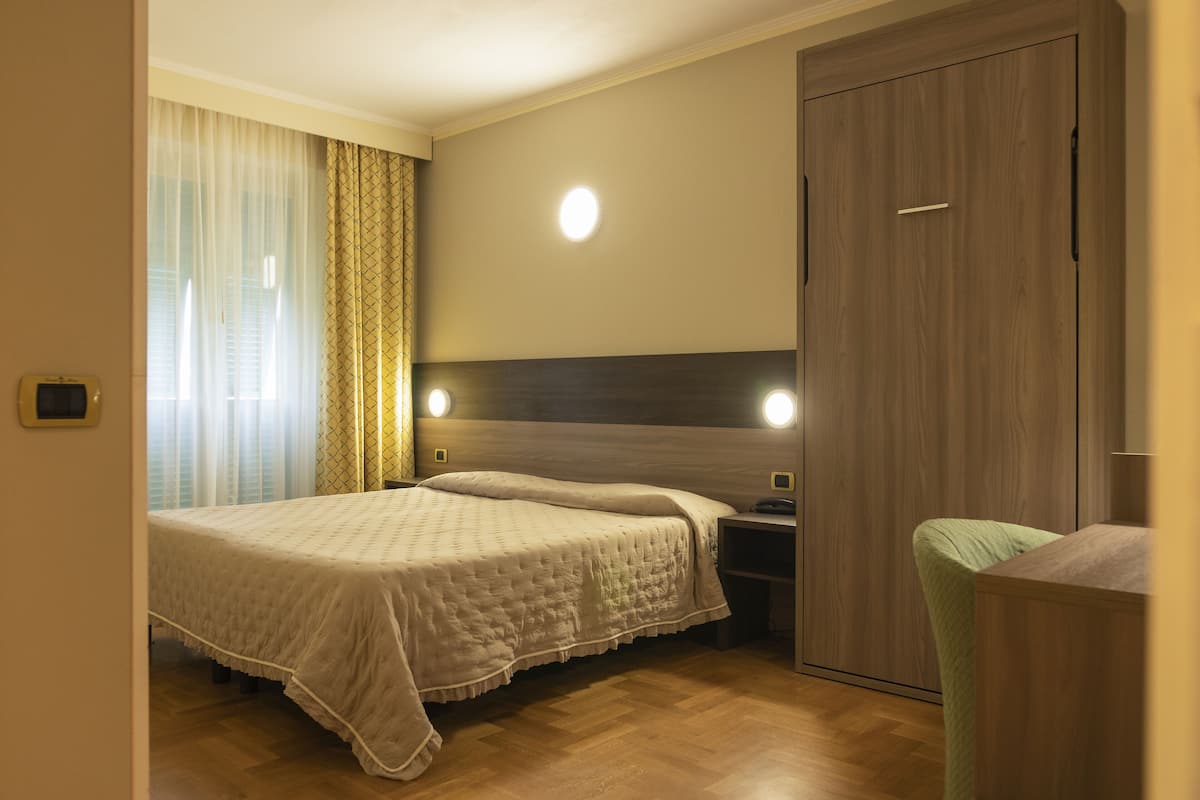 A bedroom with a double bed, bedside tables, a wardrobe, and a bedside lamp.