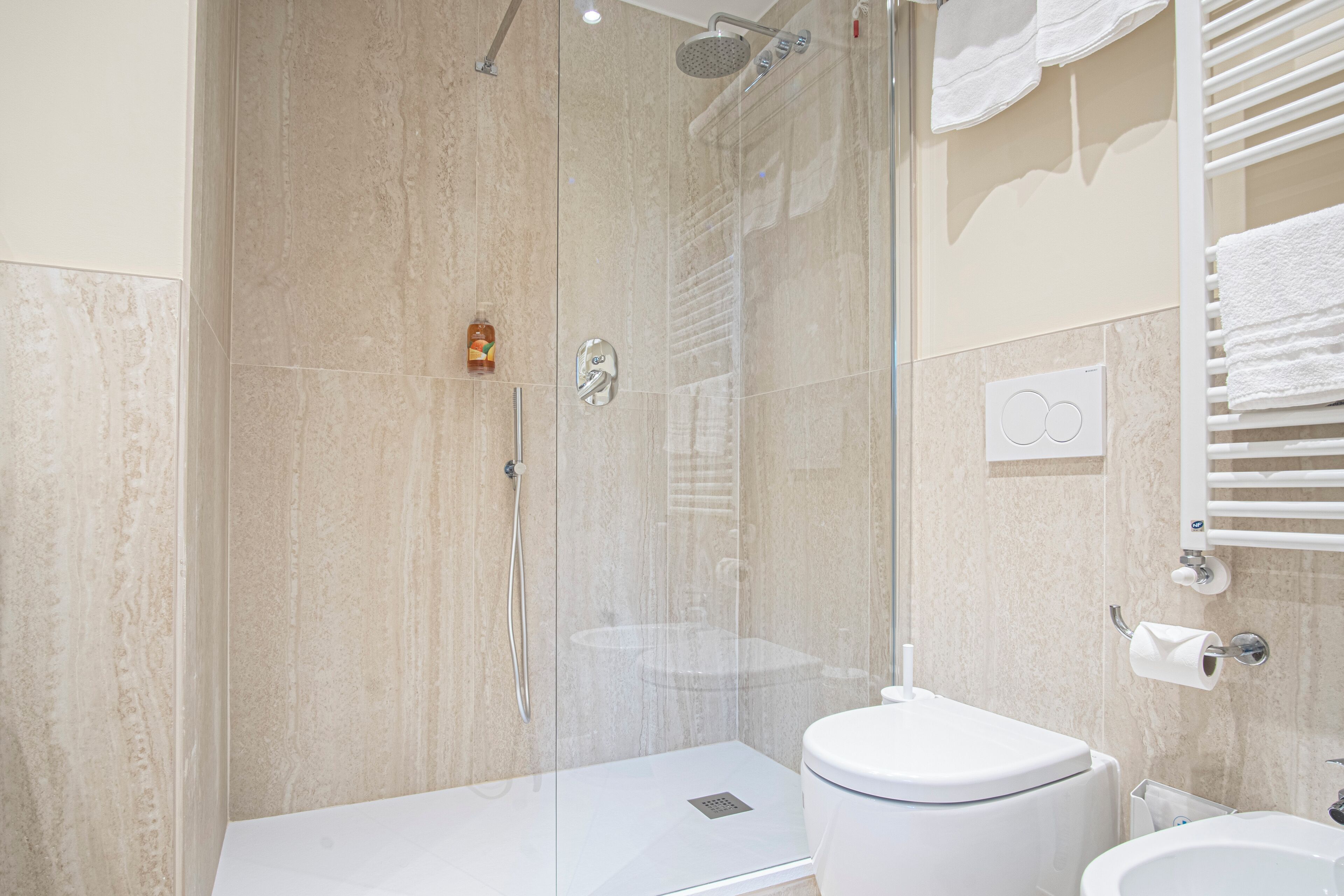 Un baño moderno con ducha de vidrio, inodoro blanco y lavamanos.