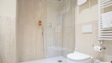 Un baño moderno con ducha de vidrio, inodoro blanco y lavamanos.