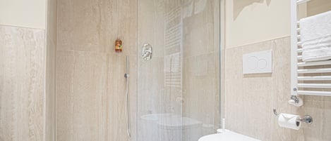 Un baño moderno con ducha de vidrio, inodoro blanco y lavamanos.
