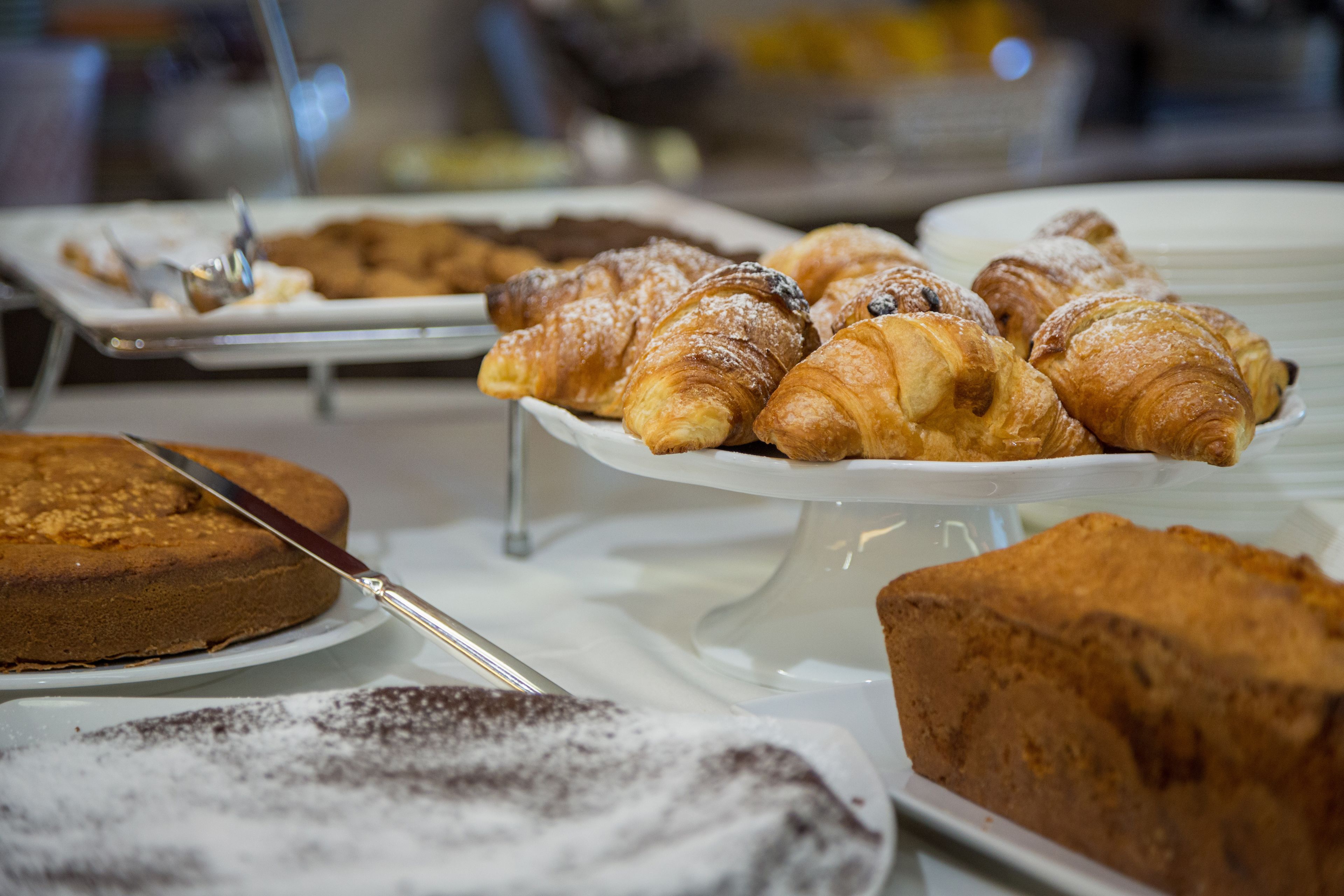 A buffet with various baked goods including pastries and cakes.