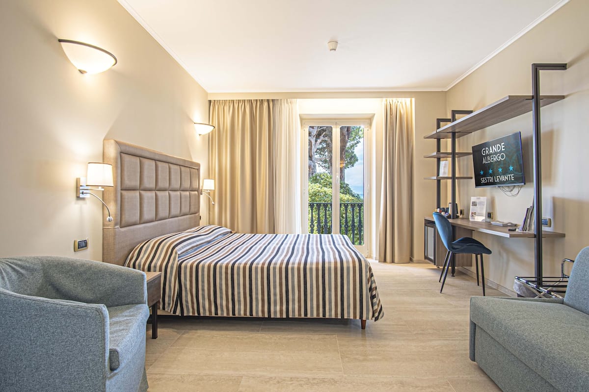 A hotel room with a bed, a desk, a chair, and a TV.