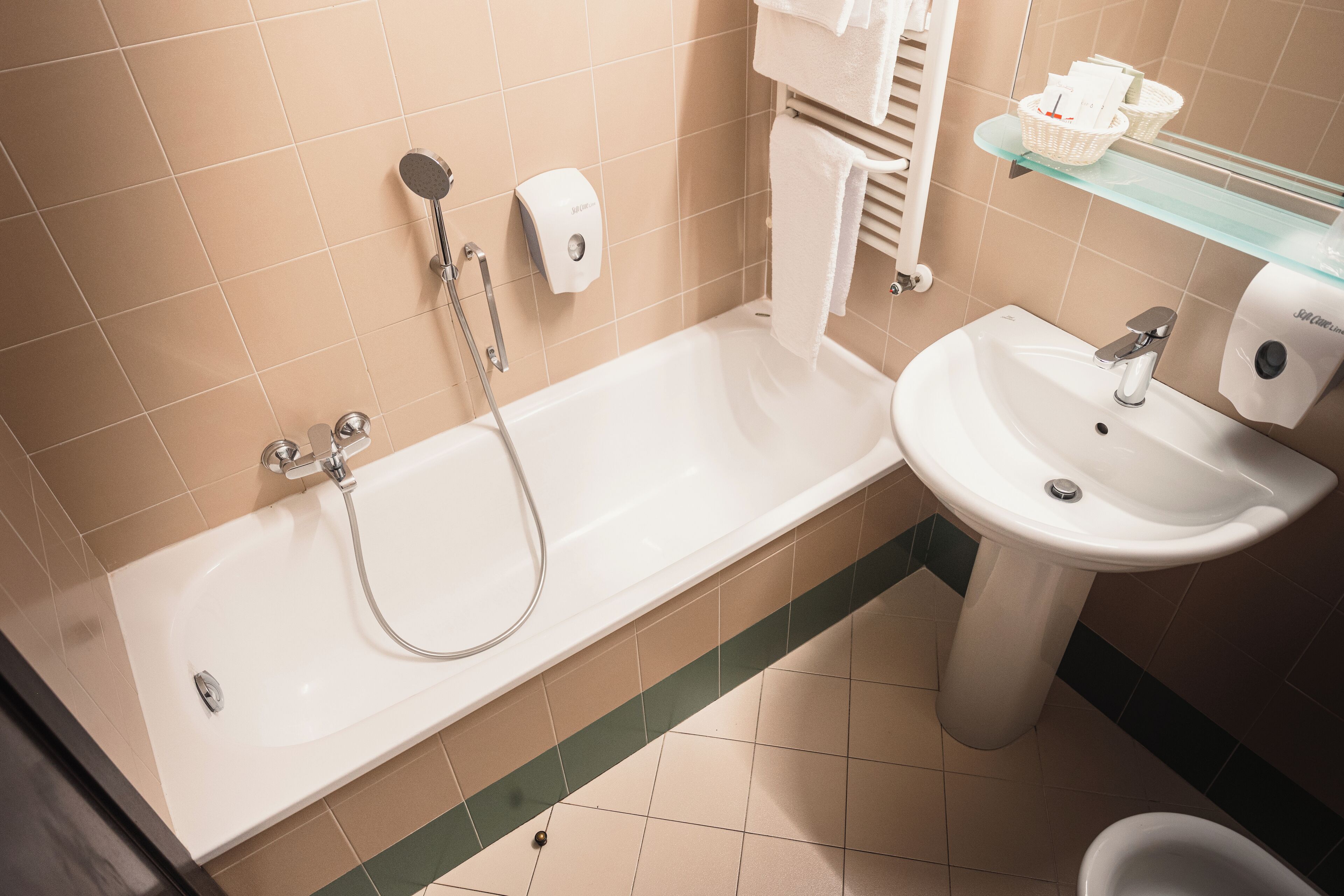 Un bagno con una vasca, un lavandino e uno scaffale in vetro con articoli da toilette.