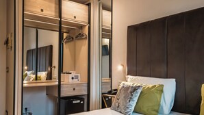 Habitación de hotel con cama, mesita de noche con bandeja de desayuno, espejo y armario.