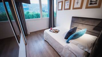 Ein Schlafzimmer mit einem Bett, einem Tablett mit Frühstücksgebäck, einem Fenster mit Blick ins Grüne und gerahmten Bildern an der Wand.