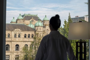 Una persona de pie en el interior, mirando un edificio histórico con múltiples cúpulas y un estilo arquitectónico clásico.