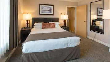 A hotel room with a large bed, two bedside tables with lamps, a framed picture on the wall, and a mirror.