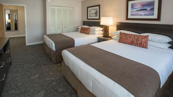A hotel room with two beds, a dresser, a mirror, a door, and a framed picture on the wall.