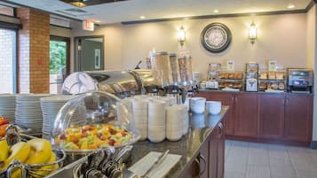 A buffet setup with various food items, including fruits and bread, and a coffee station.