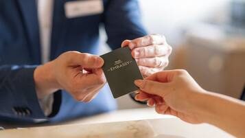 A person handing over a black card with 'THE EMBASSY' text to another individual.