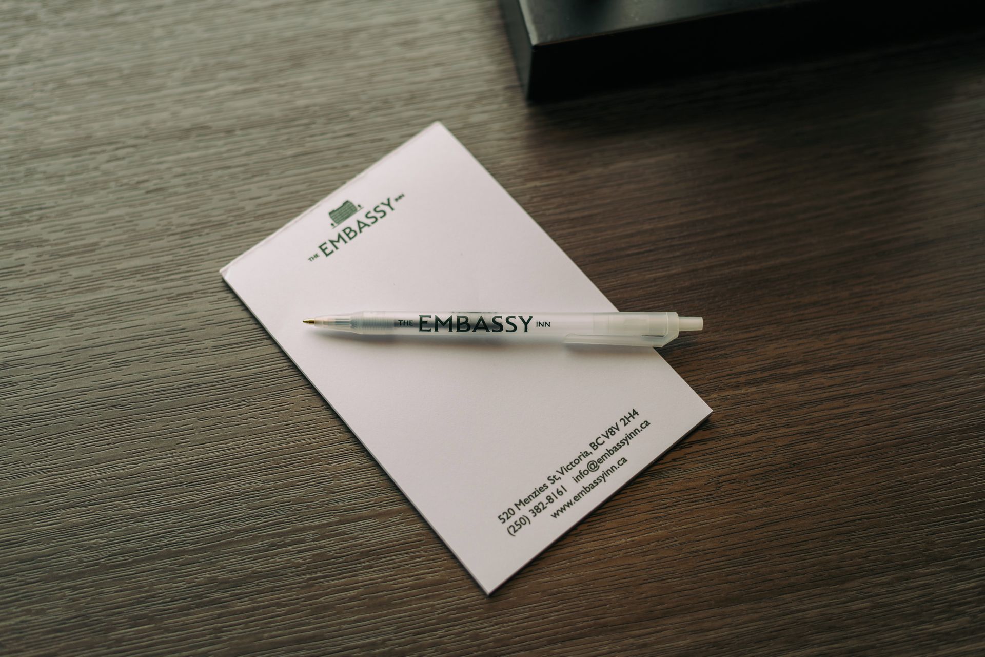 A business card for The Embassy Inn with a pen on top.