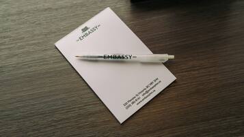 A business card for The Embassy Inn with a pen on top.
