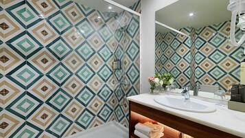 Een moderne badkamer met een wand met een geometrisch patroon, een witte wastafel, een spiegel en een douche.
