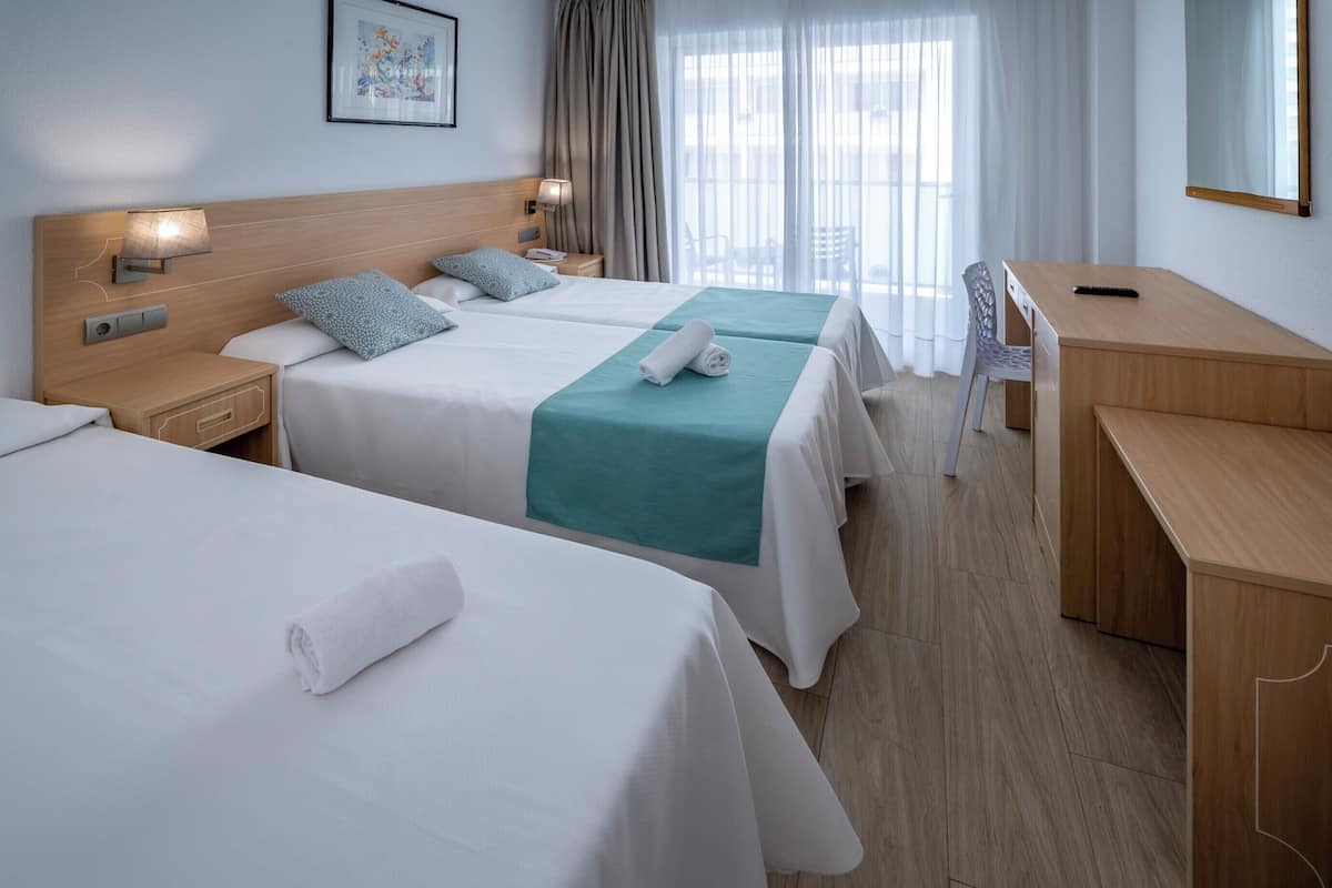 A hotel room with two beds, a desk, and a chair.