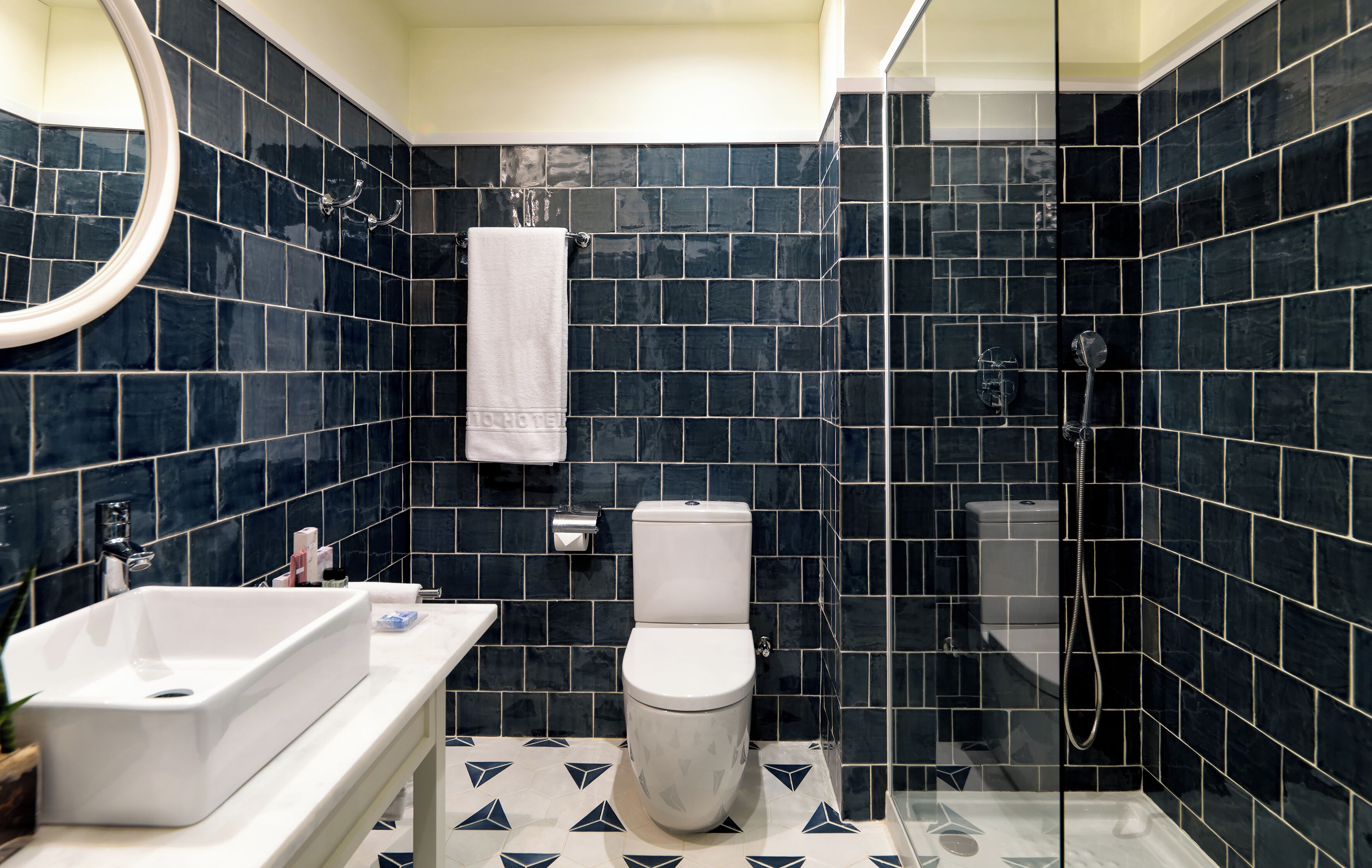 A modern bathroom with a large white sink, a toilet, and a glass-enclosed shower area.