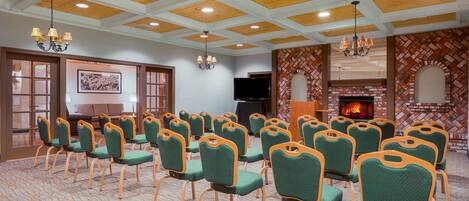 A conference room with rows of green chairs, a fireplace, and a wooden ceiling.