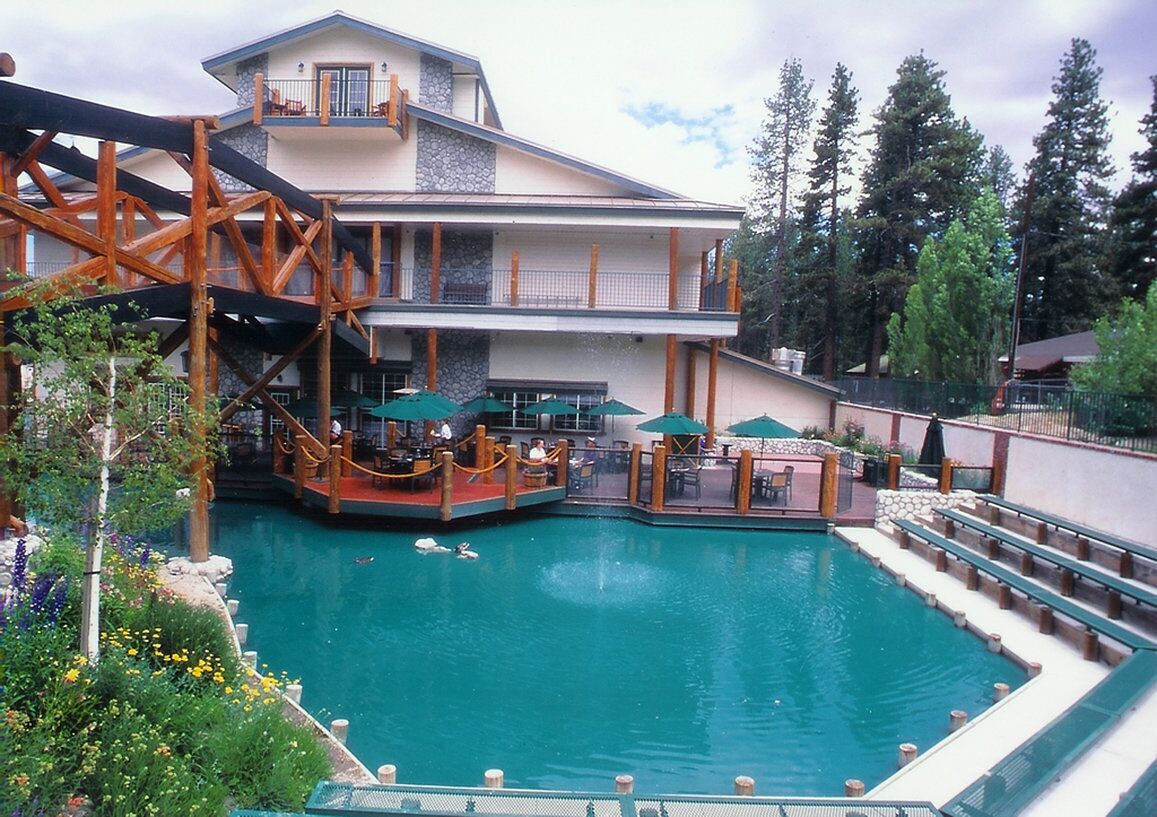 A hotel with a pool, outdoor seating, and a wooden structure.
