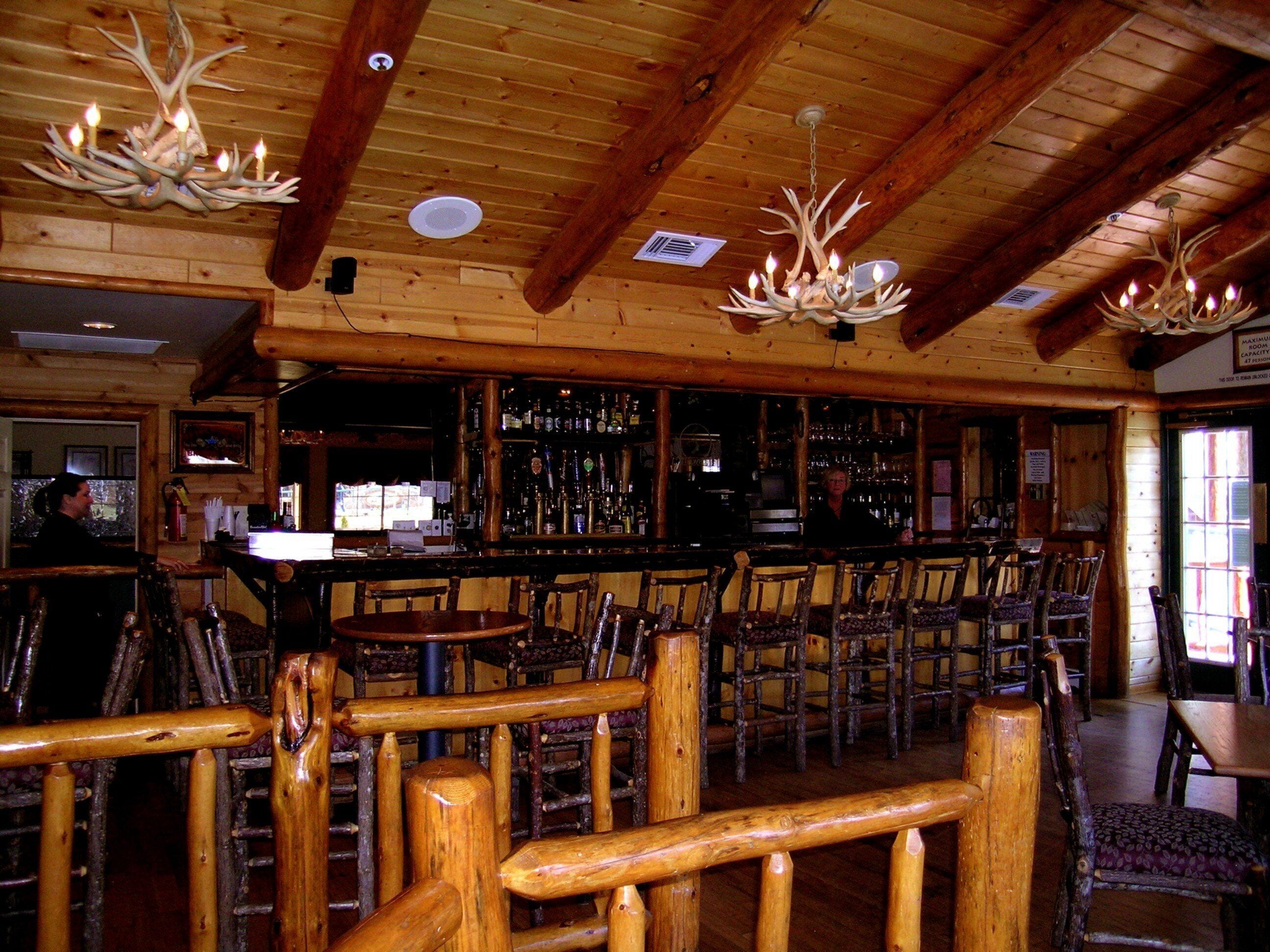 A rustic interior with wooden beams, a bar area, and seating.