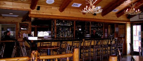 Un interior rústico con vigas de madera, una zona de bar y asientos.