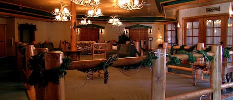 A cozy lodge interior with wooden decor, a fireplace, and a Christmas tree.