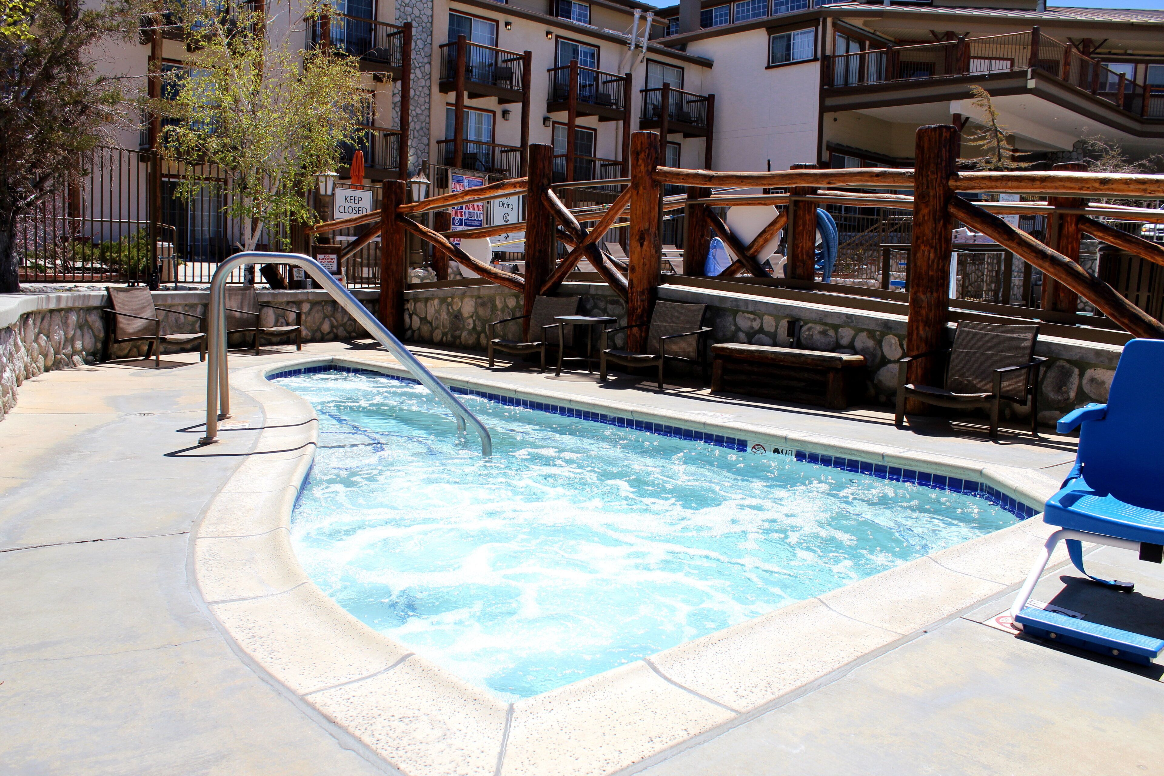 A swimming pool with a wooden deck and lounge chairs.