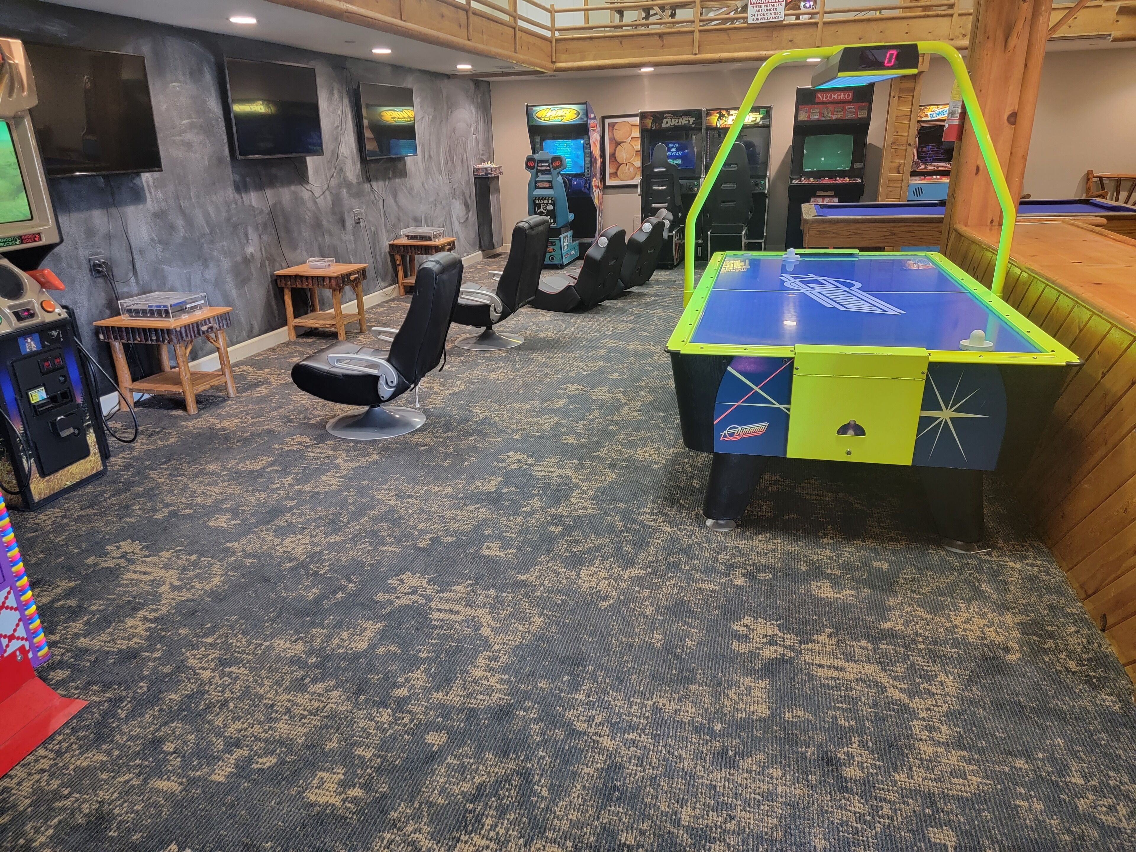 A room with multiple gaming machines, a pool table, and several chairs.