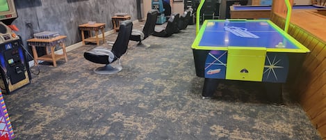 A room with multiple gaming machines, a pool table, and several chairs.