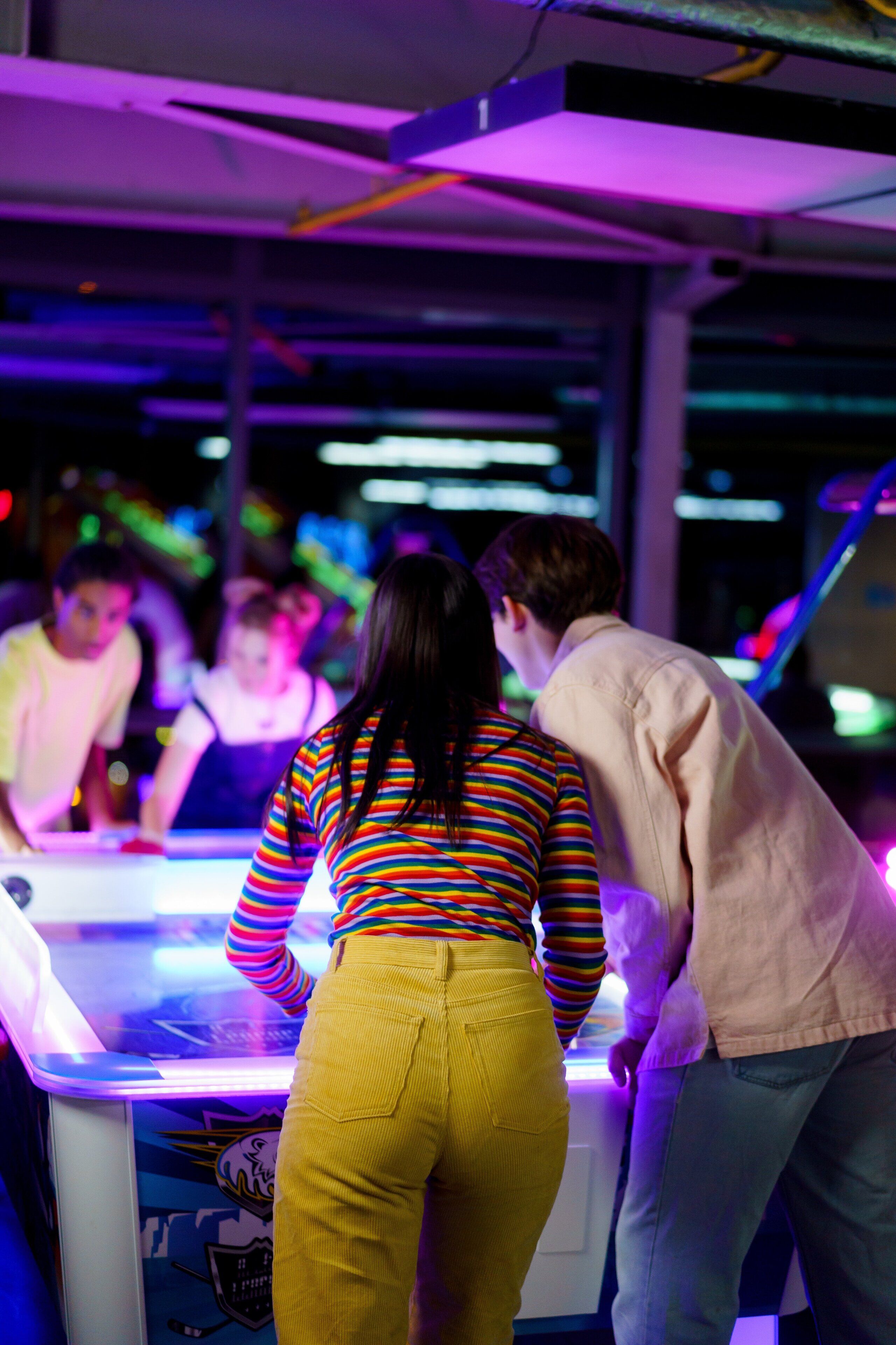 A group of people playing a video game in an arcade setting.