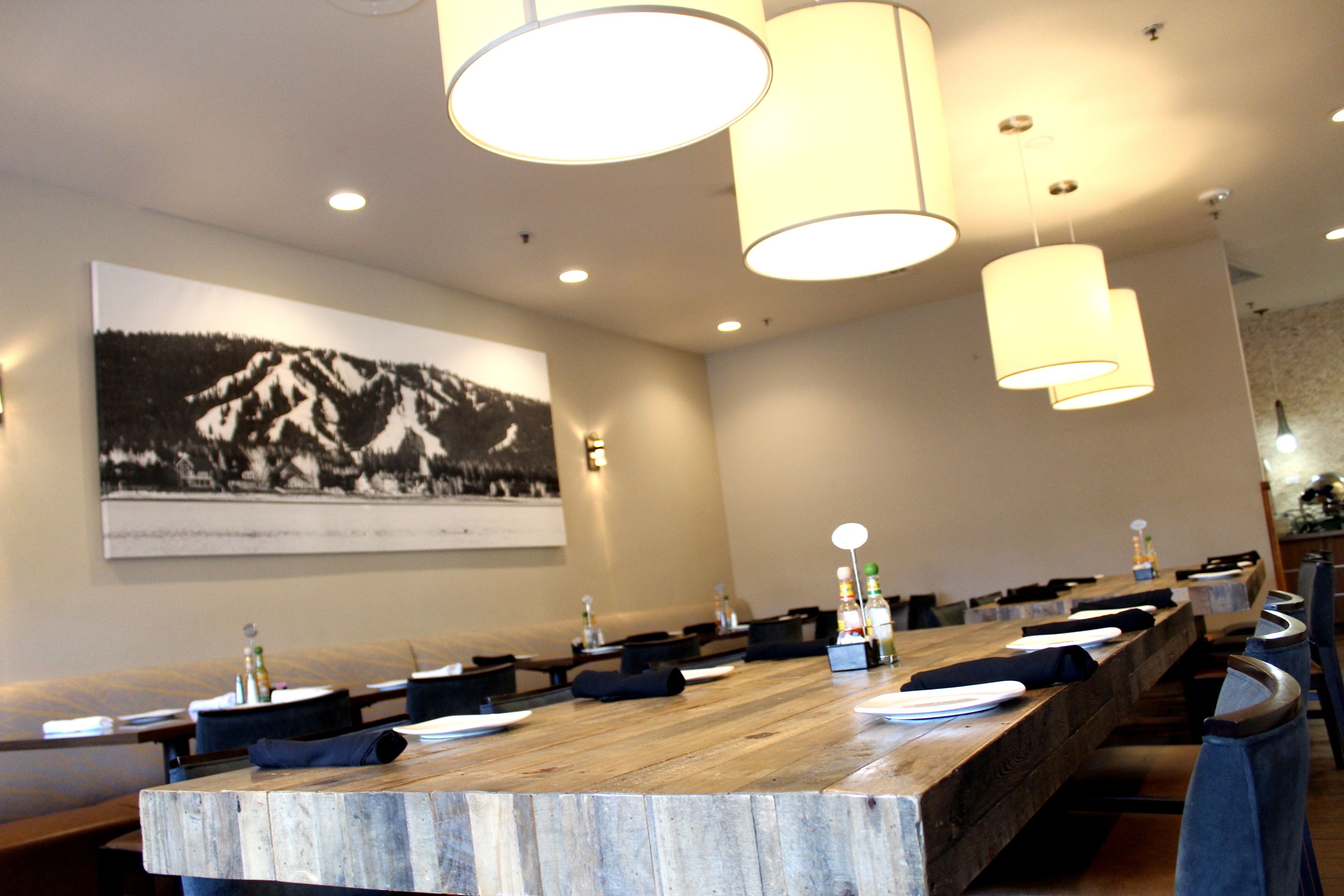 A conference room with a long wooden table, multiple chairs, and pendant lighting.