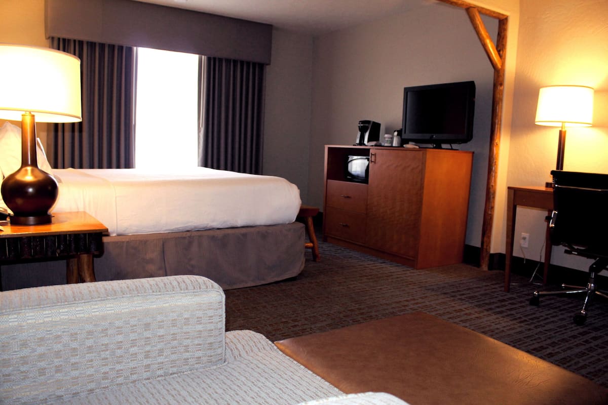 A hotel room with a bed, a desk, a television, and a lamp.