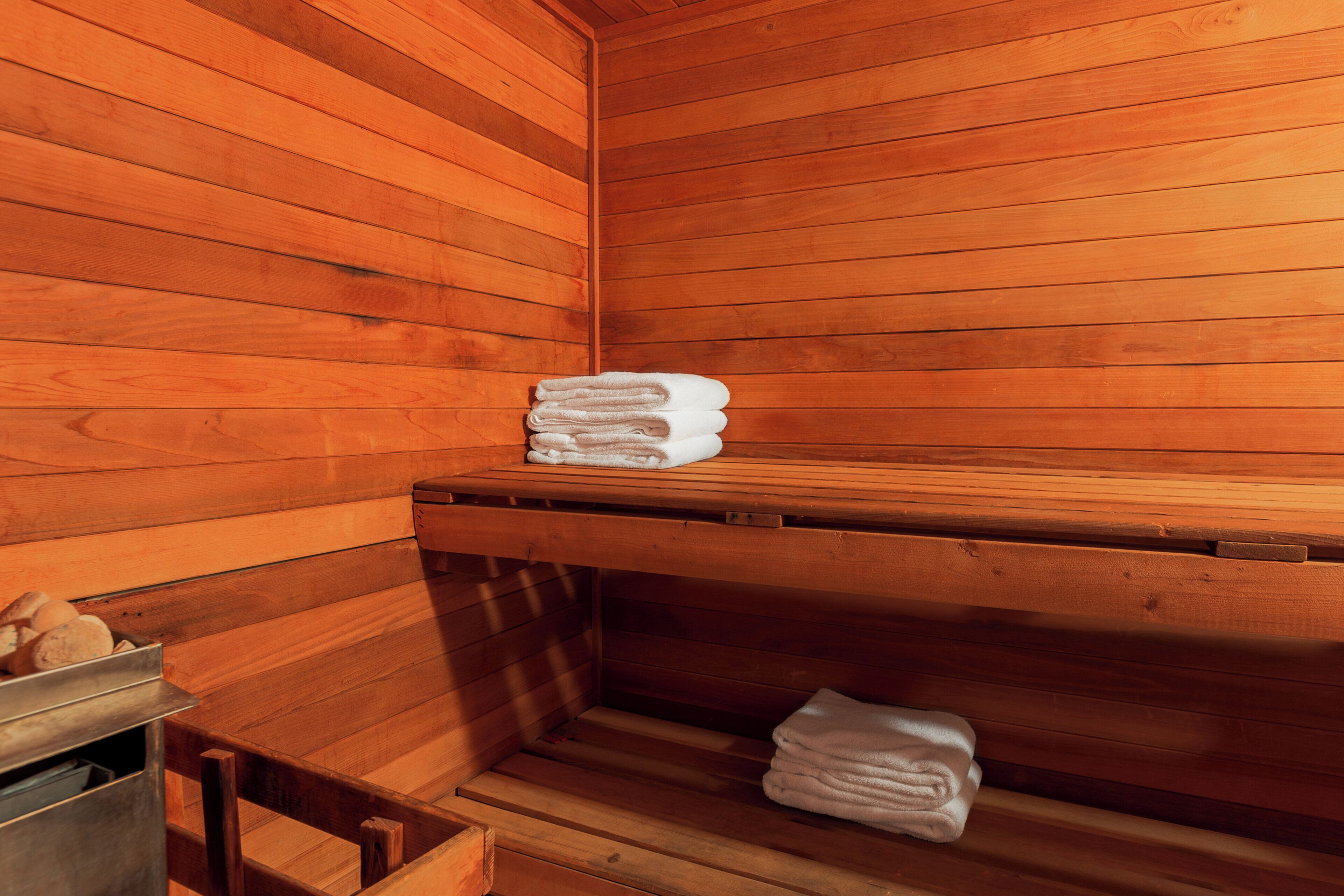 Una sauna de madera con bancos y una pila de toallas.