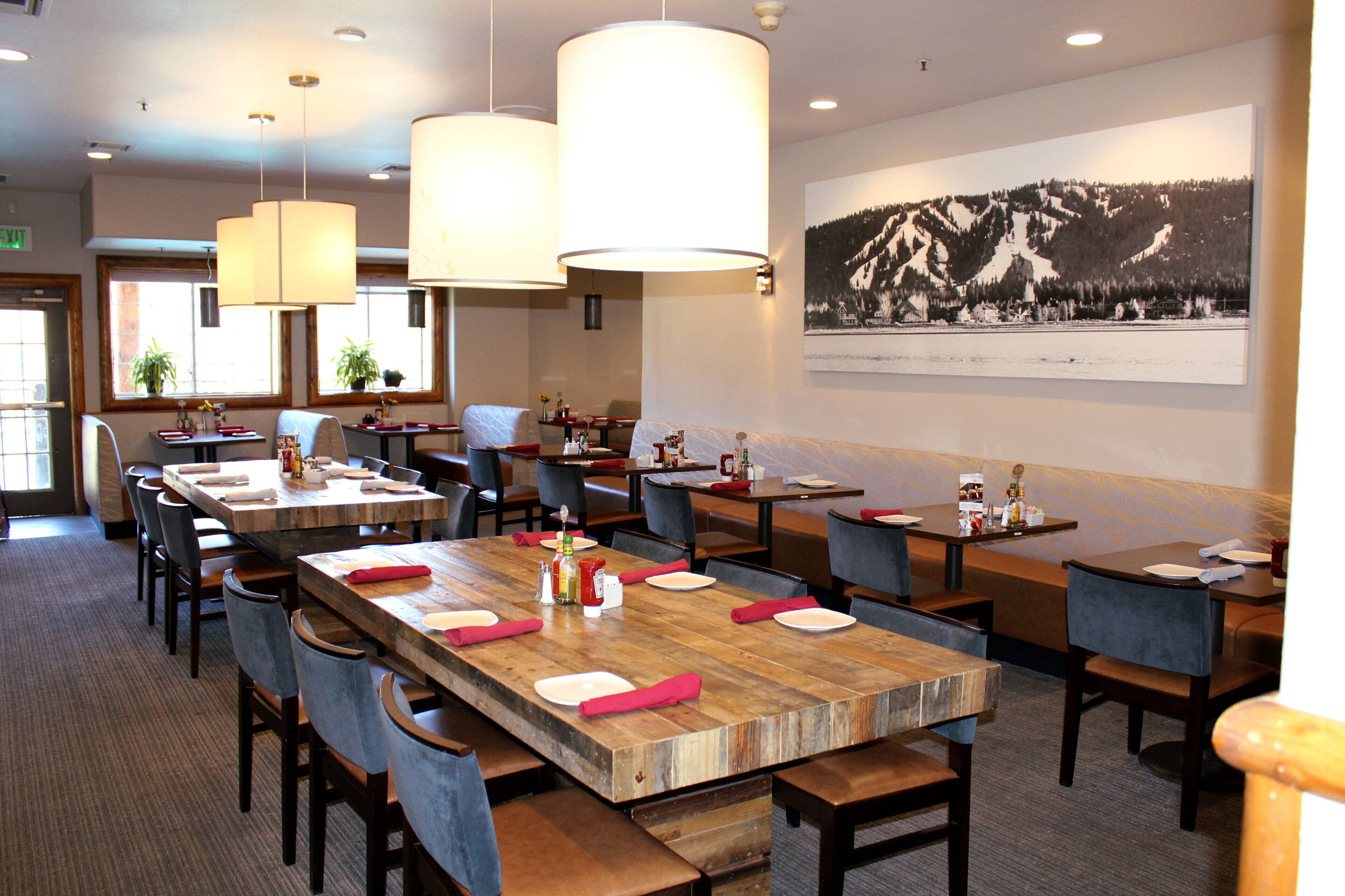 Un restaurant doté de nombreuses tables, de chaises et de lampes suspendues.