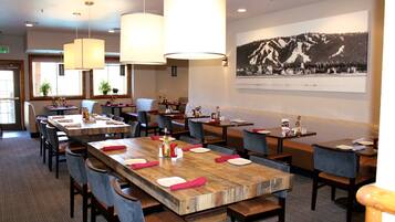A restaurant with multiple tables, chairs, and hanging lamps.