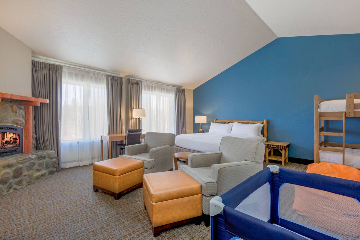 A hotel room with a stone fireplace, a bed, a blue wall, and a bunk bed.