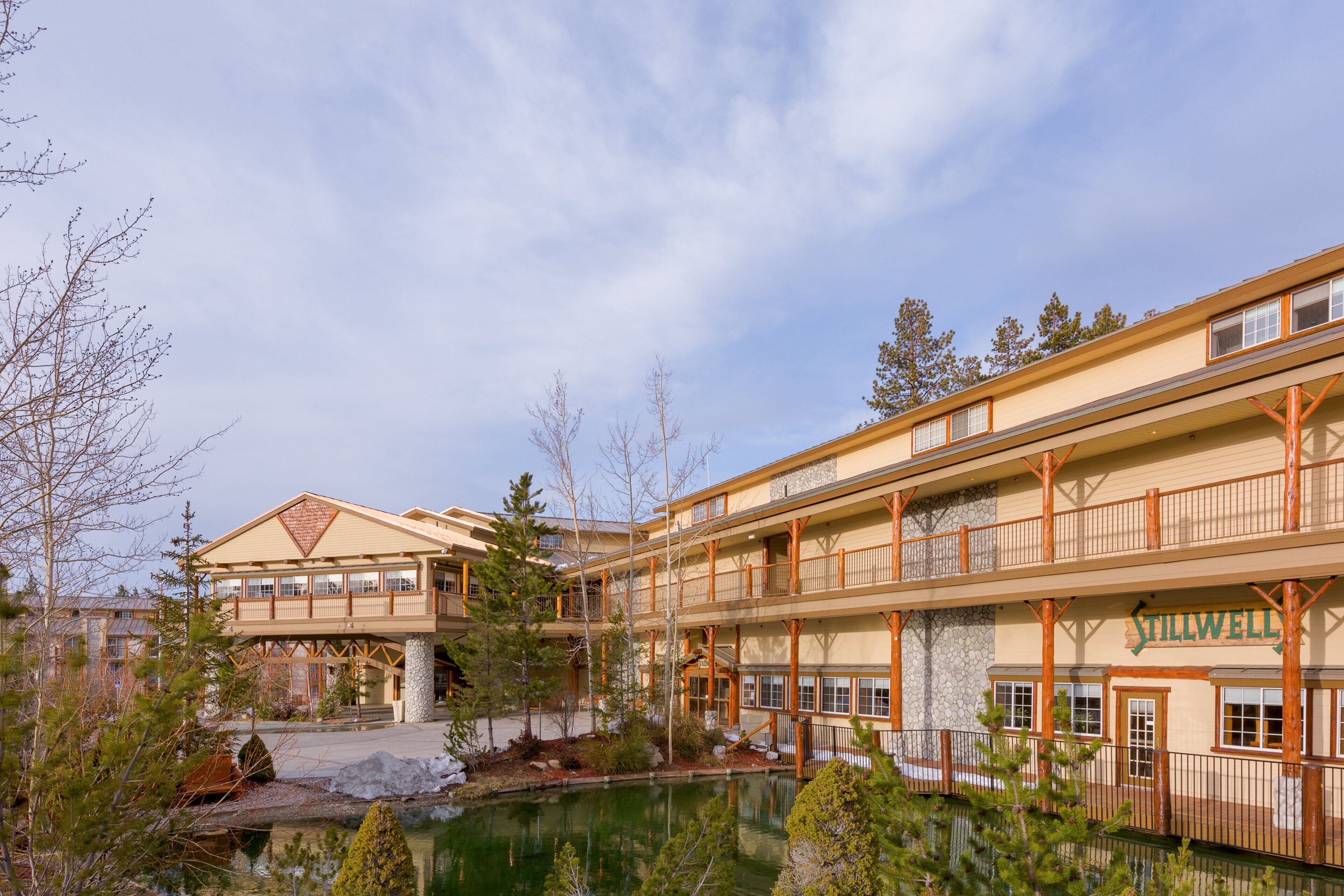 Un hôtel à plusieurs étages doté d’une piscine, d’une architecture en bois et d’une enseigne portant le nom « Stillwell ».