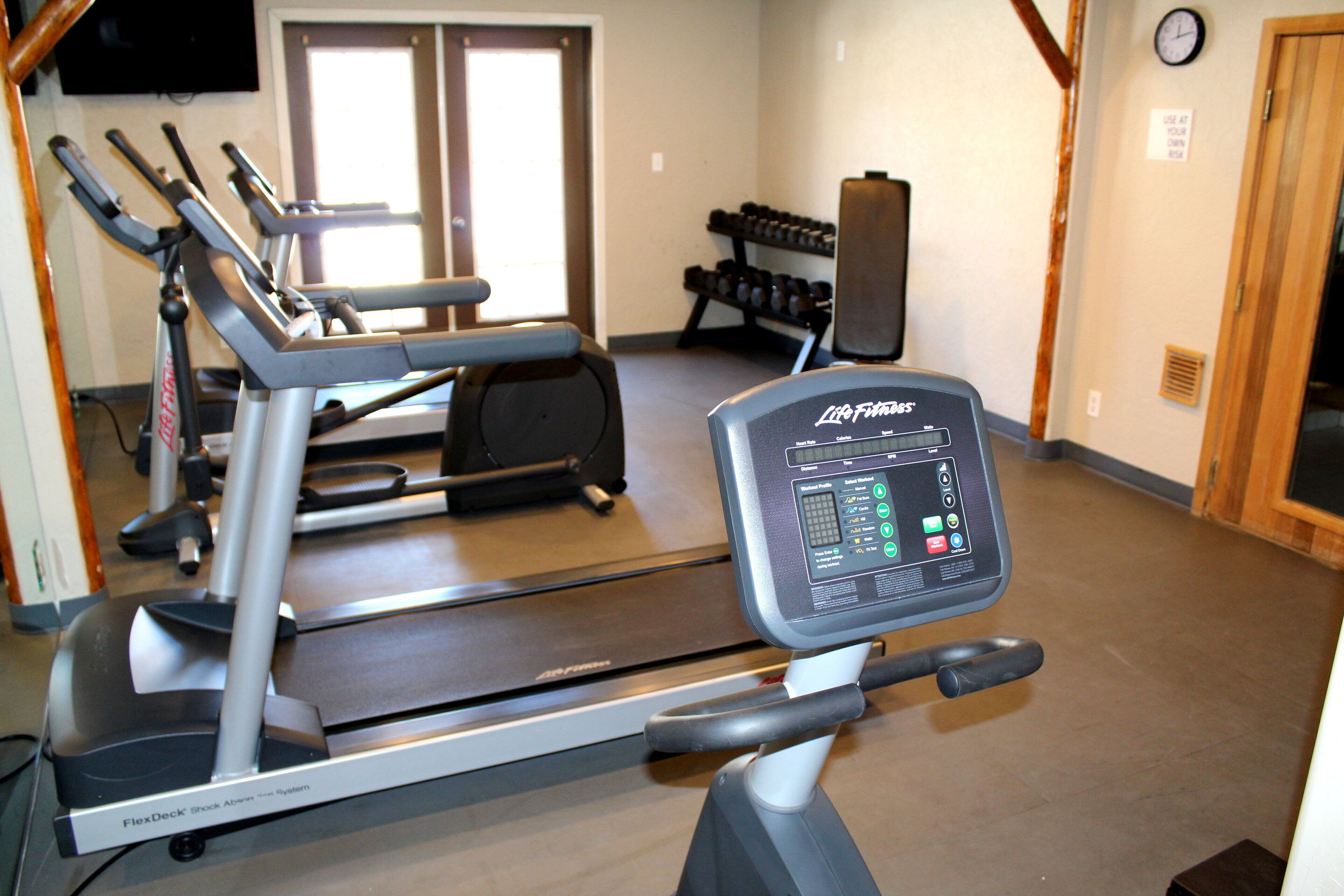 Une salle de sport équipée de tapis de course, d’haltères et d’un vélo d’appartement.