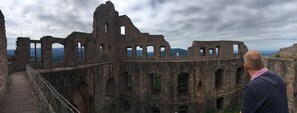 Una estructura histórica de piedra con arcos y ruinas, que incluye un sendero y una barandilla.