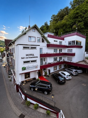 Un hotel con fachada blanca, varios balcones y un toldo rojo.
