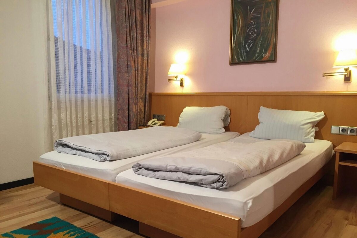 Ein Doppelbett mit Holz Kopfteil, zwei Nachttische, ein Telefon und ein Bild an der Wand.