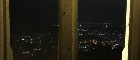 Une fenêtre donnant sur une vue de la ville la nuit.