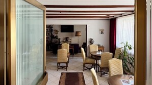 A room with a dining area, a bookshelf, and a television.